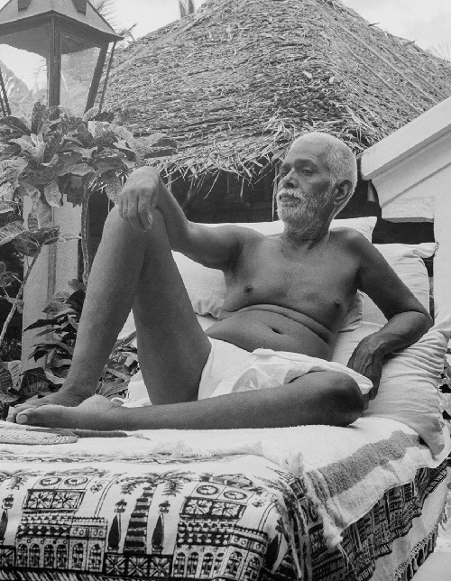 Bhagavan Sri Ramana Maharshi reclining on a couch outdoors at Sri Ramanasramam, Tiruvannamalai — teacher of Self-enquiry (atma vichara)